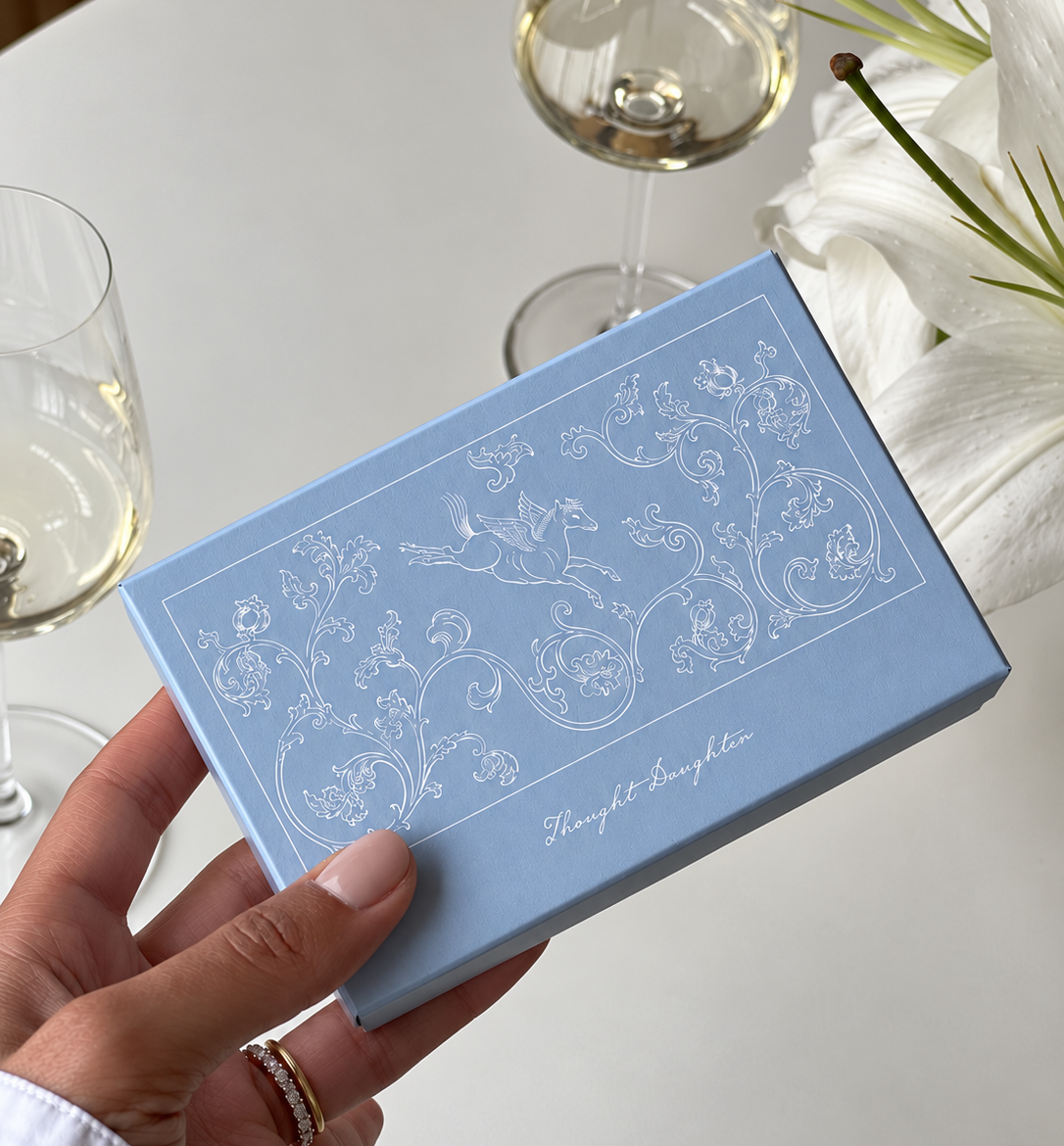 Thought Daughter deck held in a hand beside flowers